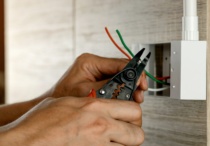 Vecteezy_Electrician-Is-Stripping-Electrical-Wires-In-A-Plastic-Box-On-A-Wooden-Wall-To-Install-The-Electrical-Outlet_3555863